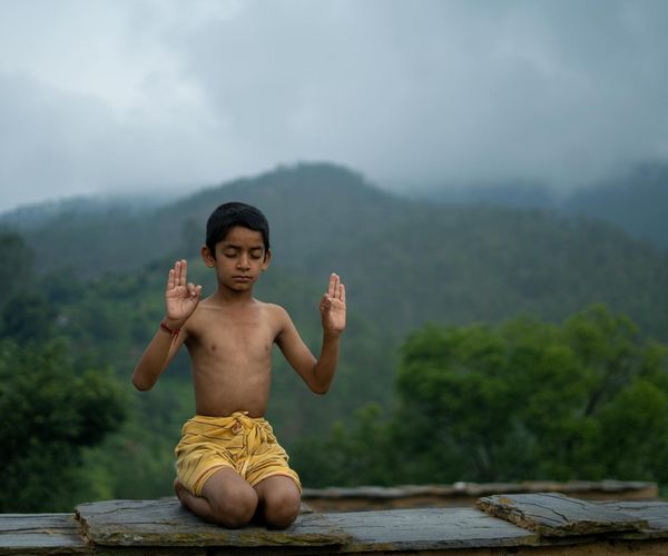 Person sitting in a lotus pose meditating peacefully.